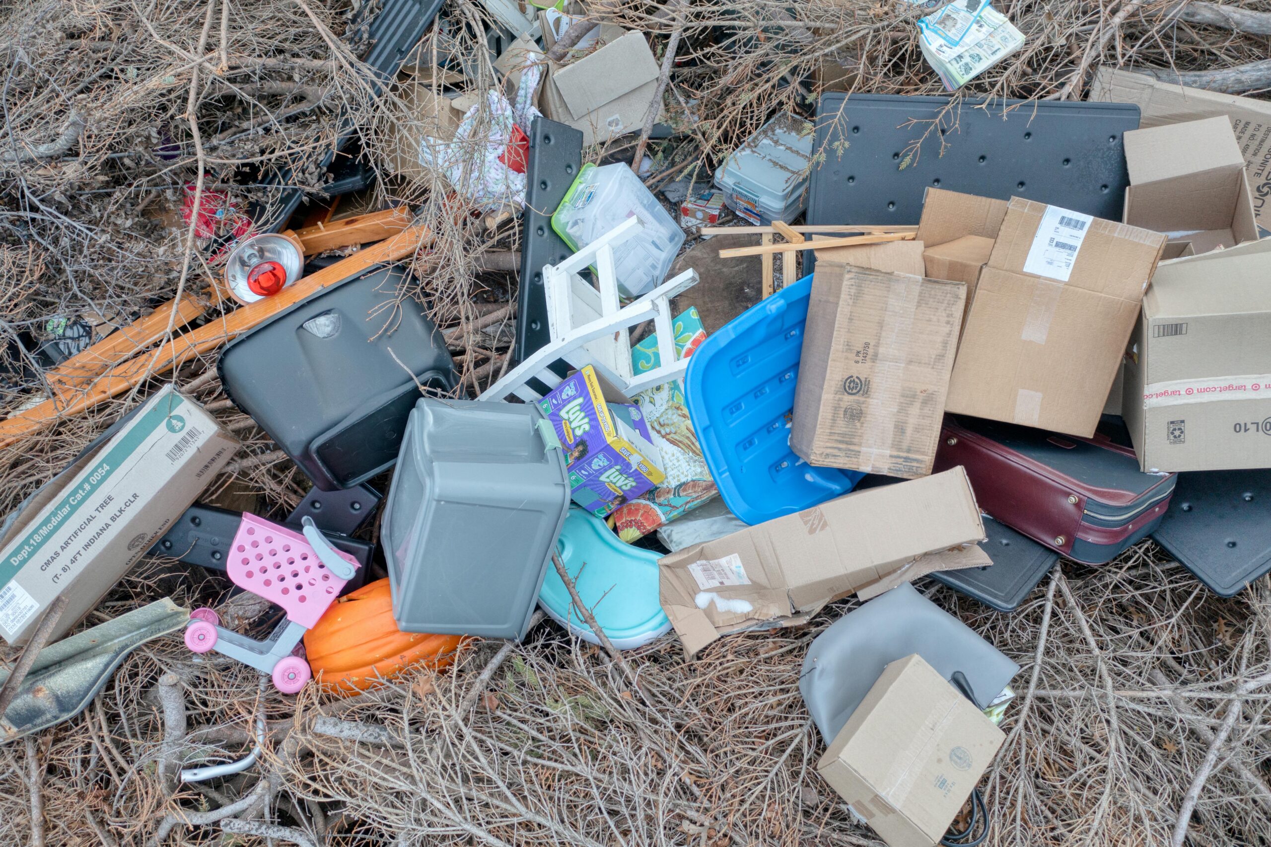 Aerial shot of mixed waste and discarded items including boxes, plastics, and branches outdoors.